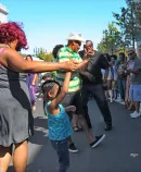 adults and children dance in the street
