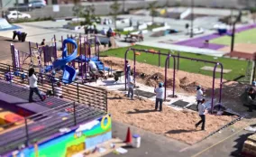 An aerial view of people using a colorful public plaza with seating, play features, and open space.
