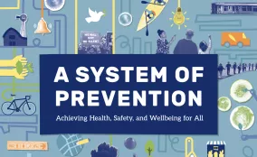 A graphic with the headline “A System of Prevention” surrounded by illustrated icons representing housing, transportation, education, food, health care, community spaces, and policy, showing how multiple systems work together to support health, safety, and wellbeing.