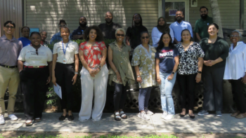 Group of diverse people standing outdoors in front of a building, smiling together in a community gathering setting