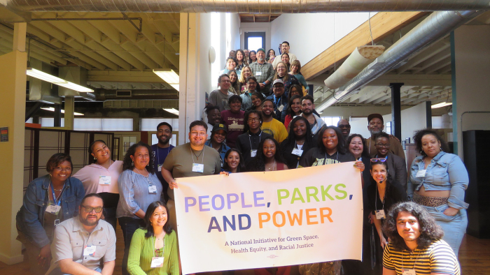 Group of partners gathered on a stairway holding a “People, Parks, and Power” banner at a national initiative convening on park equity.